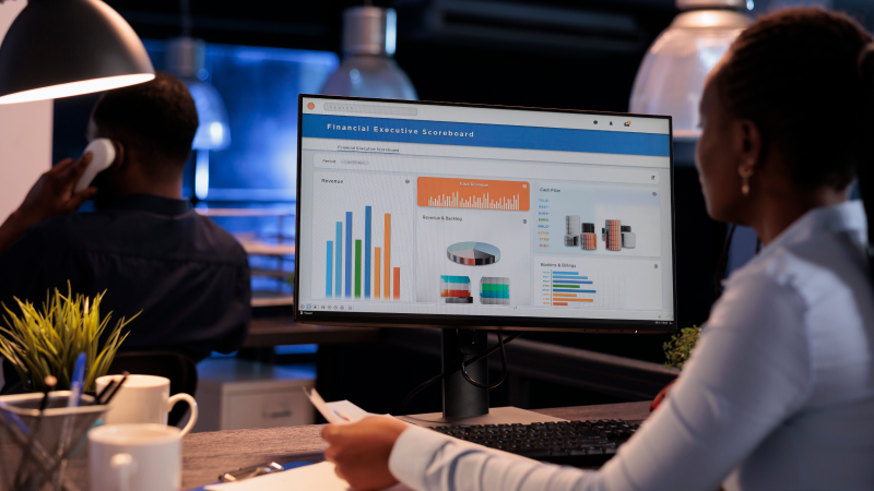Profissional analisando relatórios de vendas em dashboard de CRM no computador.