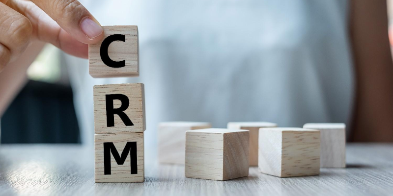 Blocos de madeira formando a palavra CRM, representando a escolha da ferramenta ideal.